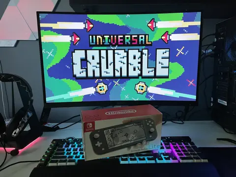 The Nintendo Switch Lite box in front of Universal Crumble on the monitor