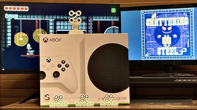 The Xbox Series S box between two monitors showing Shattering Steel